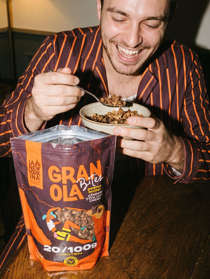 Un chico en pijama come granola junto a una bolsa de Granola Bites