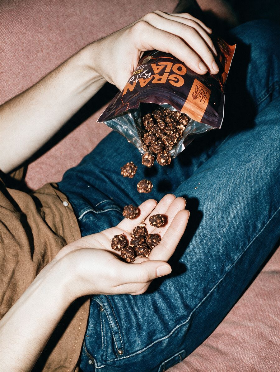 Unas manos sirven granola de chocolate desde la bolsa